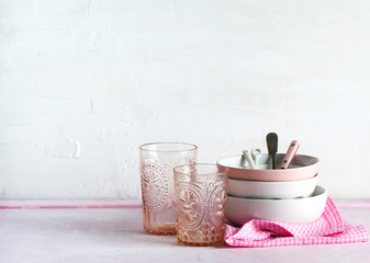 Empty pink and white bowls, glasses and kitchen utensils, copy space
