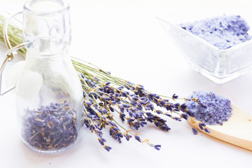 Spa and wellness setting with lavender flowers, sea salt, oil in a bottle, aroma candle on wooden white background