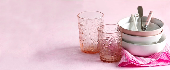Empty pink and white bowls, glasses and kitchen utensils, copy space
