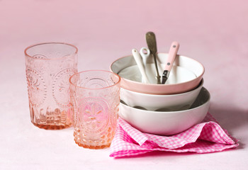 Empty pink and white bowls, glasses and kitchen utensils.
