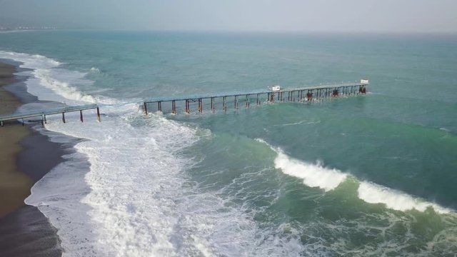 Pontile industriale sull' Oceano distrutto e crollato dalle onde tempestose.