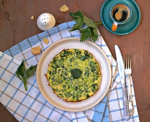 Breakfast, omelet with nettles on a white clay plate. Healthy food. Food from wild herbs. Top view, copy space.
