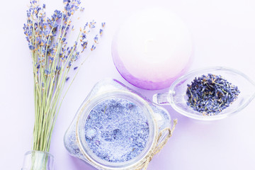 Spa and wellness setting with lavender flowers, sea salt, oil in a bottle, aroma candle on wooden white background