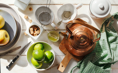 Kitchen still life with copper kettle, ceramic utensils and fruits in sunny day, top view