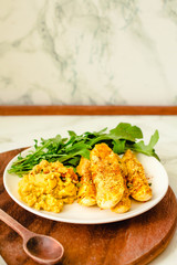 Crispy zucchini fries with garlic hummus sausea nd arugula on round wooden board. Copy space on a...