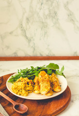 Crispy zucchini fries with garlic hummus sausea nd arugula on round wooden board. Copy space on a white marble background. Tone.
