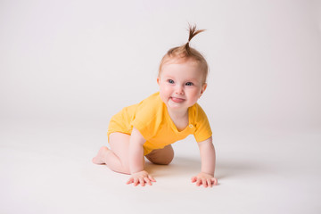 healthy baby is 6 months, baby girl smiling in a yellow bodysuit on a white background