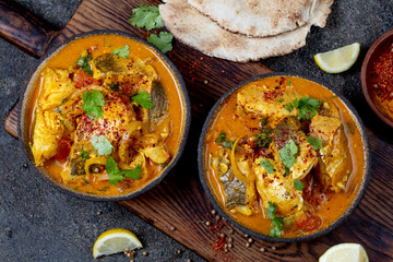 INDIAN FOOD. Traditional KERALA FISH CURRY with naan bread, gray plate, black background 