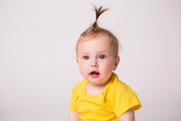 healthy baby is 6 months, baby girl smiling in a yellow bodysuit on a white background