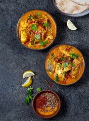 INDIAN FOOD. Traditional KERALA FISH CURRY with naan bread, gray plate, black background 