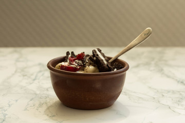 Banana vegan ice cream with cherries and oreo cookies on a white marble background.