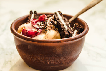 Banana vegan ice cream with cherries and oreo cookies on a white marble background.Close-up.