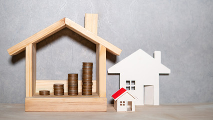 Obraz na płótnie Canvas Property or real estate investment concept. Home mortgage loan rate. Saving money for future retirement. Miniature house model with coins stacked in wood house frame on wooden table.