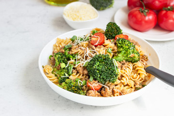 Pasta with meat sauce, cherry tomatoes and broccoli. Mediterranean cuisine with pasta ingredients - olive oil, broccoli and tomatoes.
