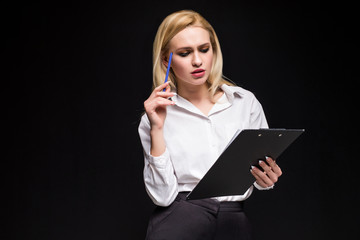 Smiling young blonde businesswoman taking notes and looking at camera isolated on grey background