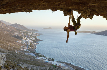 Young woman climbing in cave at sunset