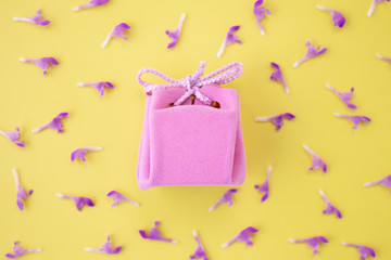 Pink gift box on a yellow background with flowers. Festive concept.  Flat lay, top view 