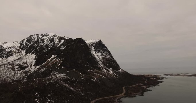 Aerial drone shot of a road that runs along the mountain range by the sea on the beautiful island of Lofoten in Norway