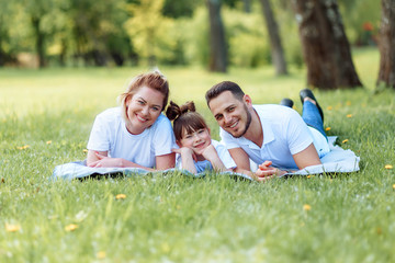 Fototapeta premium Happiness and harmony in family life. Happy family concept. Young mother and father with their daughter in the park.