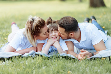 Naklejka na ściany i meble Happiness and harmony in family life. Happy family concept. Young mother and father with their daughter in the park. Happy family. Carefree, happylife.