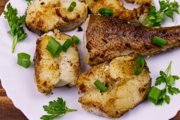 Roasted pollock in white plate on a wooden table