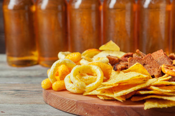 Lager beer and snacks on wooden table. Nuts, chips, pretzel