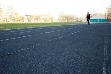 Obraz premium one caucasian male is doing a sprint start. running on the rubber track. Track and field runner in sport uniform. energetic physical activities. outdoor exercise, healthy lifestyle