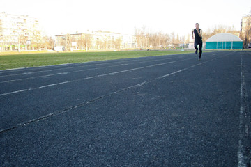Fototapeta premium one caucasian male is doing a sprint start. running on the rubber track. Track and field runner in sport uniform. energetic physical activities. outdoor exercise, healthy lifestyle