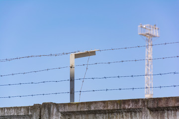 Concrete wall, against the backdrop of barbed wire, the concept of prison, salvation, refugee, lonely. Barbed wire fence detail.  Silhouette barbed wire and a watchtower