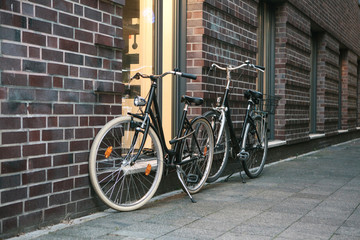 Fototapeta na wymiar Bicycles are parked next to a brick wall of a building on a city street.
