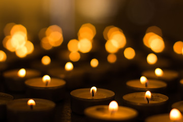 candles yellow fire illumination and unfocused bokeh effect background inside religion building in church service time twilight environment
