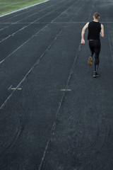 Fototapeta na wymiar caucasian man doing a sprint start. running on the stadium on a track. Track and field runner in sport uniform. energetic physical activities. outdoor exercise, healthy lifestyle. vertical top view