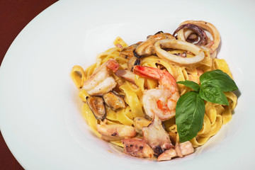 Pasta with shrimps, calamari, fresh parmesan cheese on a wooden table, terrace, seafood, fish dish. Fresh food.