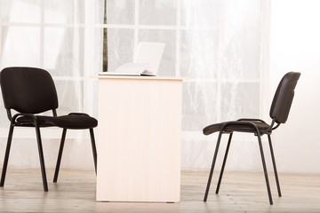 Office space, a table and two chairs. Office empty without people. People went to the census. Laptop and notebook for notes on the table.