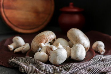 Fresh champignon mushrooms group on the table. Fresh vegetables mushrooms - the concept of healthy proper nutrition. Dark Food Photography