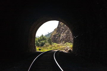 light with a landscape at the end of a stone railway tunnel with beautifully lit rails in the...