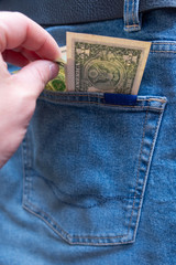 Hand pulls money from the back pocket of jeans.