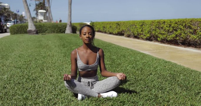 Black woman doing yoga on lawn