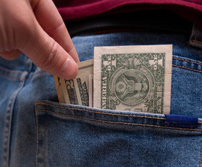 Hand pulls money from the back pocket of jeans.