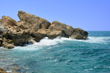 Fototapeta na wymiar the waves running on the stony coast against the background of the blue sky