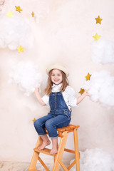 A smiling cute little girl flies in the sky with clouds and stars. Little astrologer Little...