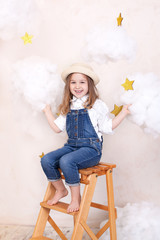A smiling cute little girl flies in the sky with clouds and stars. Little astrologer Little traveler. The concept of preschool education of the child. Close-up face portrait