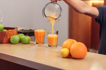 Two servings of fruit juice with a straw in glass cups stand on the bar near the fruit vases. Detox cleansing concept