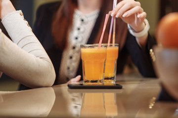 Two servings of fruit juice with a straw in glass cups stand on the bar near the fruit vases. Detox cleansing concept