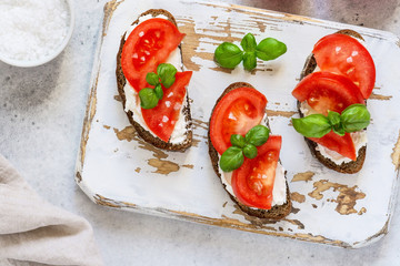 Toasted bread with tomatoes, ricotta (cream cheese), basil