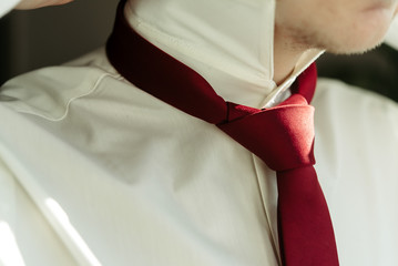 happy gorgeous handsome groom getting ready dressed in the morning on background of a room