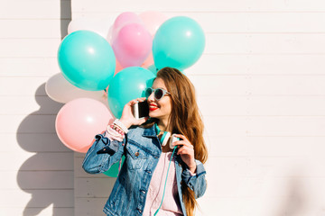 Stylish cheerful girl in sunglasses waiting for party start and speaking to friend by the phone....