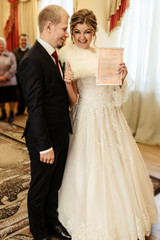 happy gorgeous bride and stylish groom holding official document wedding register, emotional moment, ceremony