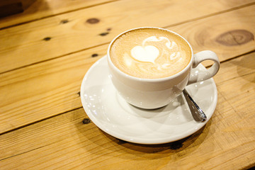 beautiful stylish stunning white cup with latte and a heart on a wooden table