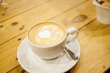 beautiful stylish stunning white cup with latte and a heart on a wooden table